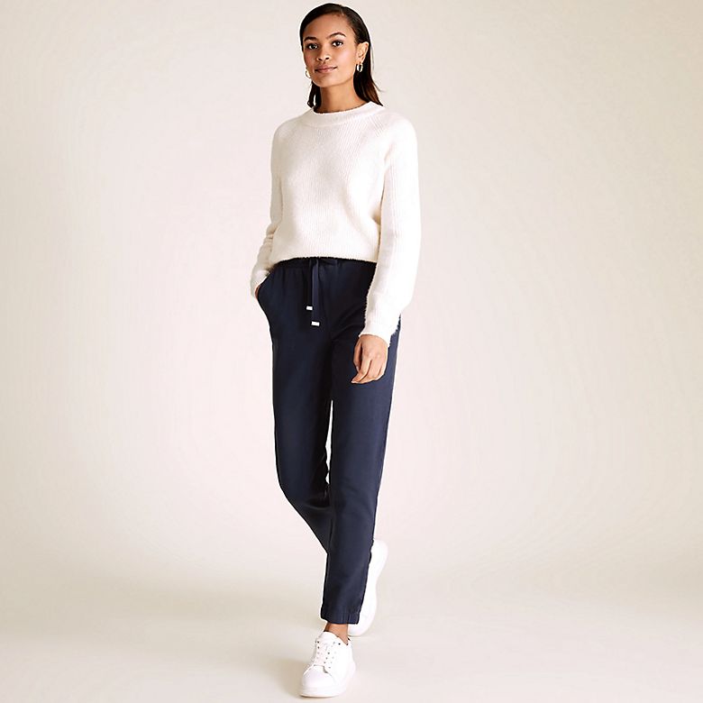 Woman wearing white cashmere jumper, navy joggers and white trainers