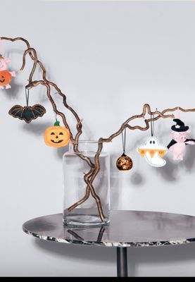 Assorted Halloween decorations hung on tree. Shop Halloween decorations
