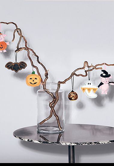 Assorted Halloween decorations hung on tree. Shop Halloween decorations
