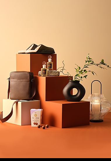 Group of gifting items including chocolates, leather belt, weekend bag and men’s grooming products. Shop men’s Eid gifts.