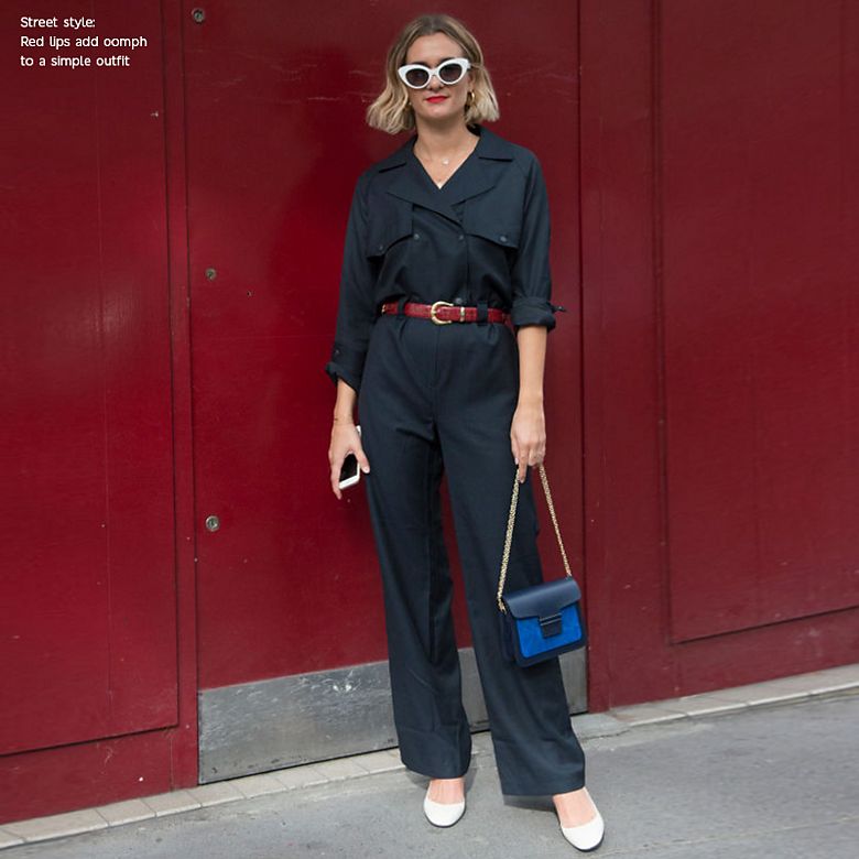 Woman wearing black jumpsuit, red lipstick and white sunglasses