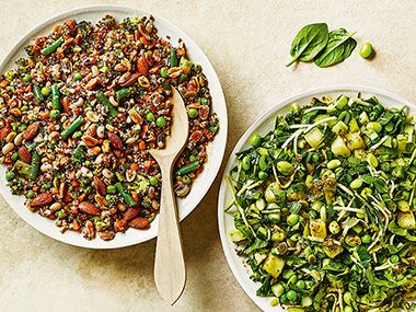 Two bowls of grain salad topped with beans and herbs