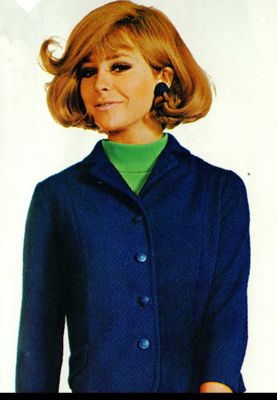 Woman wearing a blue wool skirt suit with a green top, 1967