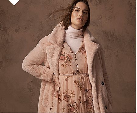Model wears a pink shearling coat over a pink floral-print midi dress and pink roll-neck jumper