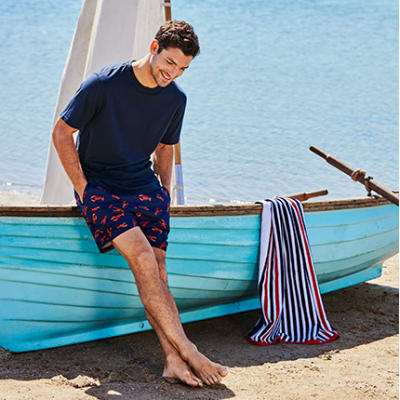 Man modelling swim shorts and T-shirt reclining on a boat