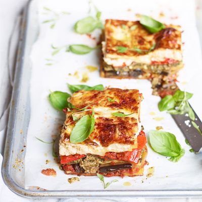 Slices of vegetable lasagne n a tray with red pepper and fresh basil