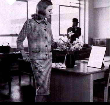 Woman wearing coordinated printed skirt suit in the office, 1959