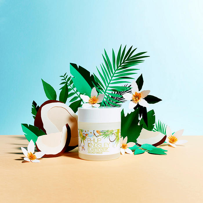 Philip Kingsley Coconut Breeze Elasticizer surrounded by coconuts and palm leaves