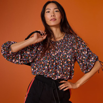 Woman wearing floral-print blouse and jeans. Shop women’s shirts and blouses 