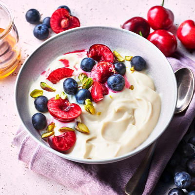 Yoghurt topped with blueberries, cherries, pistachios and honey