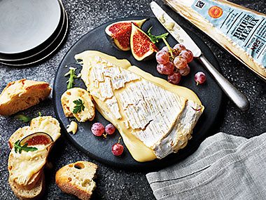 Wedge of brie de Meaux with French bread, grapes and figs