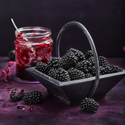 A basket of blackberries with berry jam