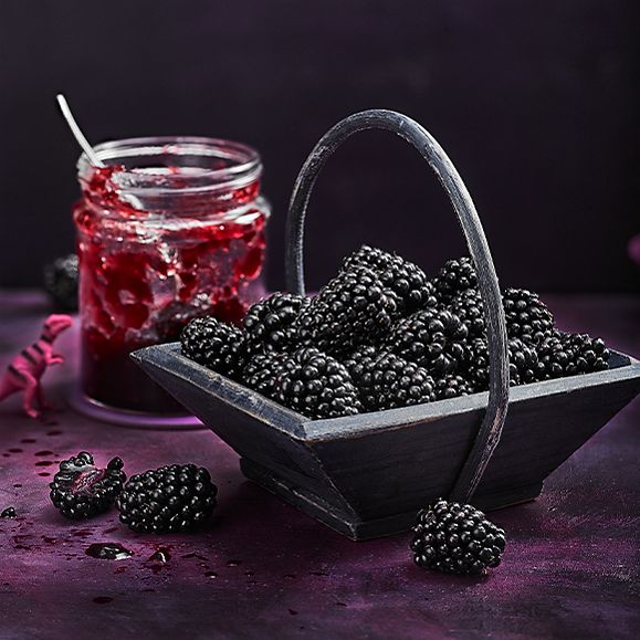 A basket of blackberries with berry jam