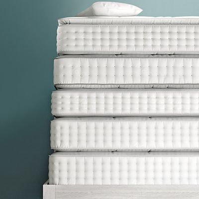 Five mattresses stacked on a bed frame with a pillow on top