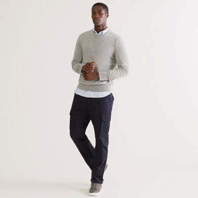 Man wearing navy chinos, blue shirt, grey crew-neck jumper and grey trainers