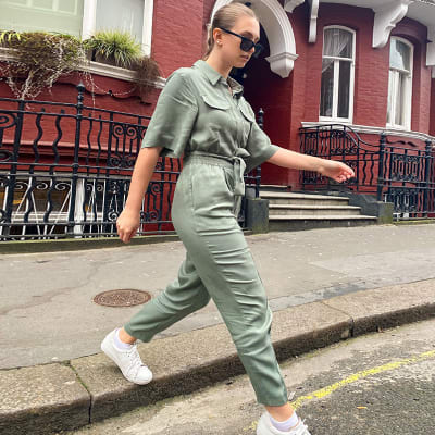 Woman wearing khaki jumpsuit and white trainers