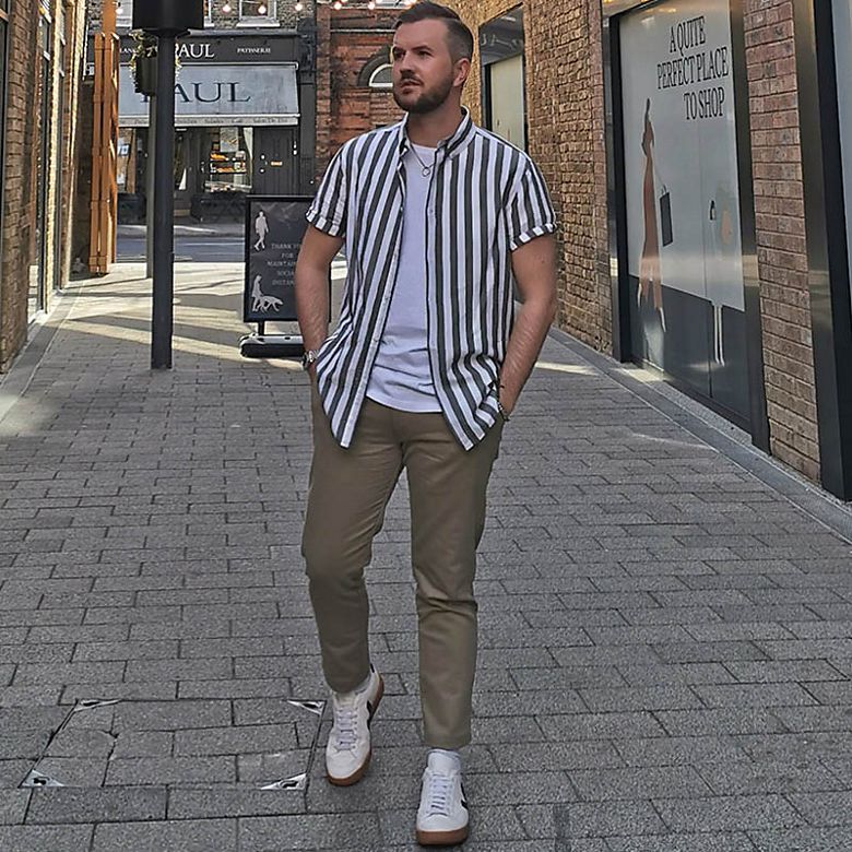 Man wearing short-sleeved striped shirt open over white T-shirt and chinos
