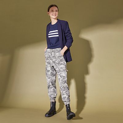 Woman wearing camo cargo trousers with a navy stripe top, navy blazer and chunky boots 