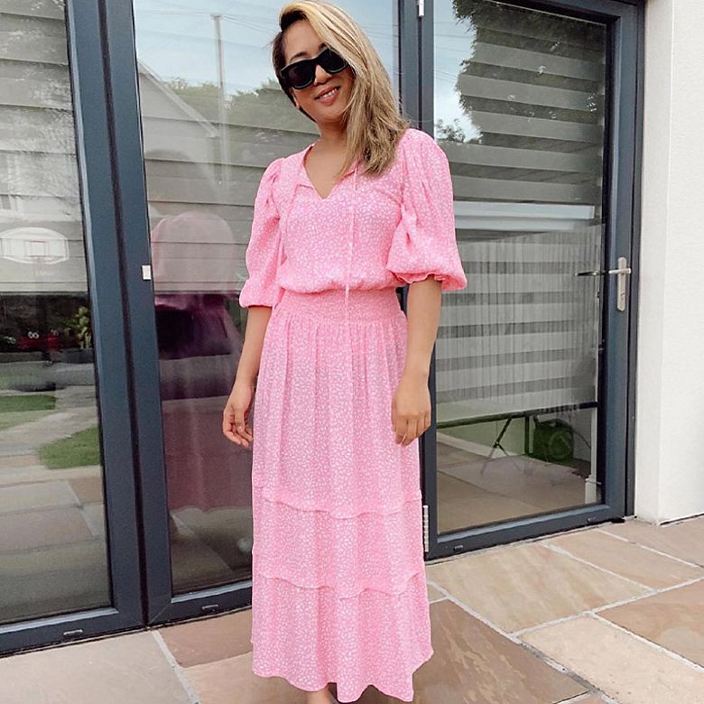 Woman wearing pink puff-sleeve dress and white trainers