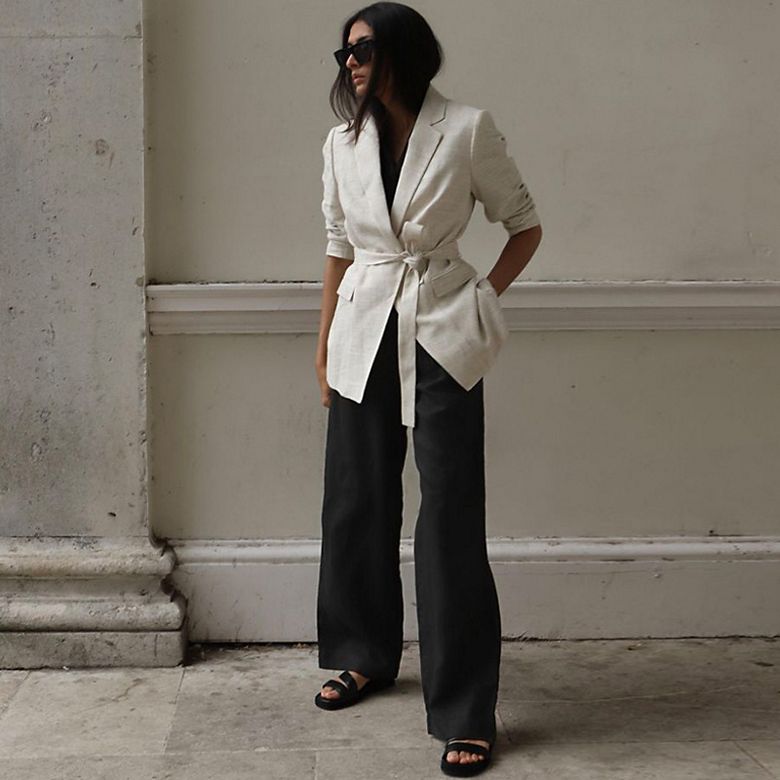 Woman wearing cream belted blazer and black wide-leg trousers