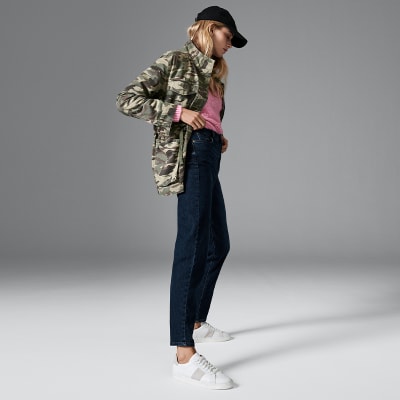 Woman wearing camo shacket, pink T-shirt and mom jeans