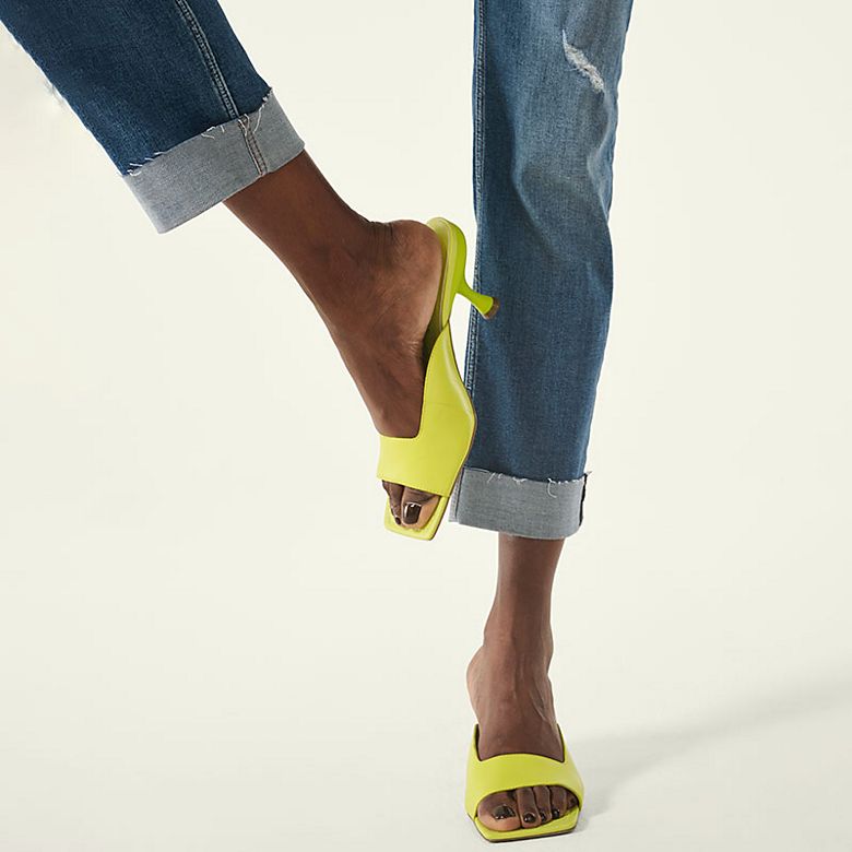 Woman wearing jeans and lime green kitten heel mules. Shop the mules. 