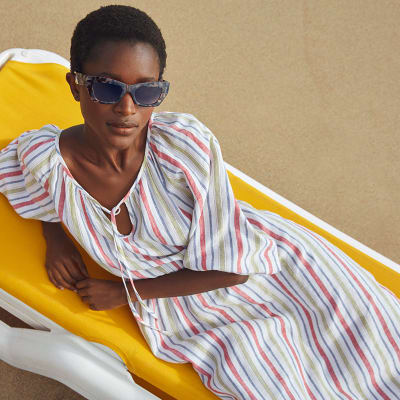 Woman wearing striped maxi dress and tortoiseshell sunglasses. Shop dresses. 