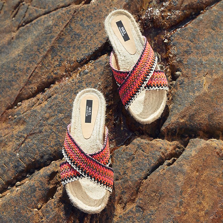 Woman’s cross-strap slider sandals on rock. Shop sandals. 