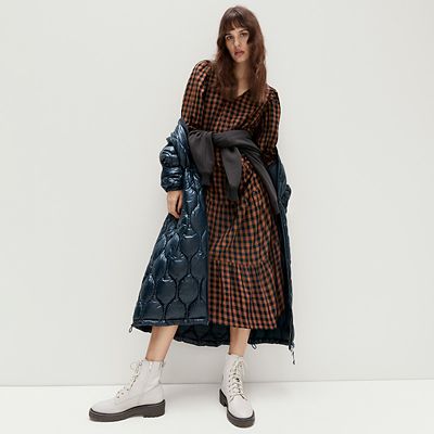 Woman wearing checked dress with cream biker boots. Shop women’s boots