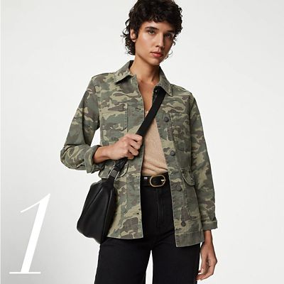Woman wearing casual summer jacket in camouflage print with a cross-body bag and black trousers. Shop women’s cotton summer jackets. 