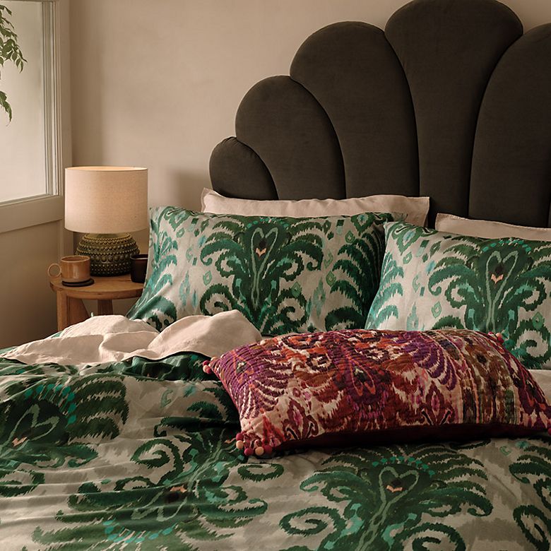 Bed with scalloped velvet headboard and maximalist green bedding . Shop our homeware trends