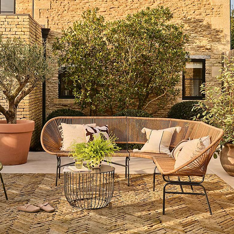 Outdoor rattan garden sofa and wire coffee table with cushions and rugs. Shop garden furniture