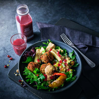 Bowl of falafel and chargrilled vegetable salad with a glass of fruit smoothie