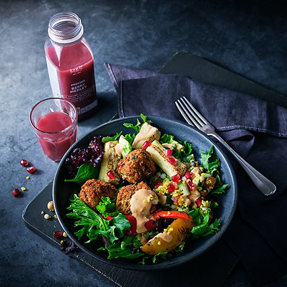 Bowl of falafel and chargrilled vegetable salad with a glass of fruit smoothie