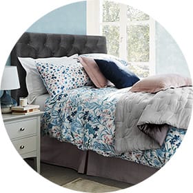 Patterned bed set next to a bedside table and lamp