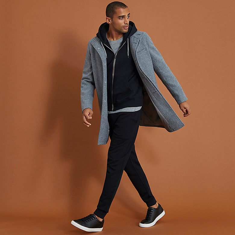 Man wearing black joggers with grey coat