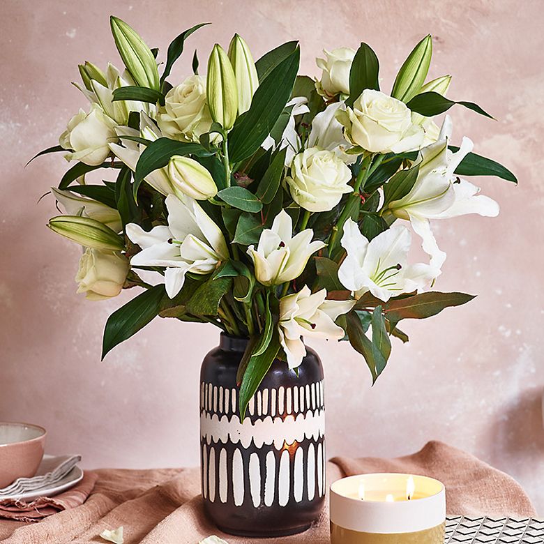 Black and white vase filled with white lilies and roses