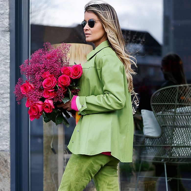 Woman wearing a green suit with pink heels