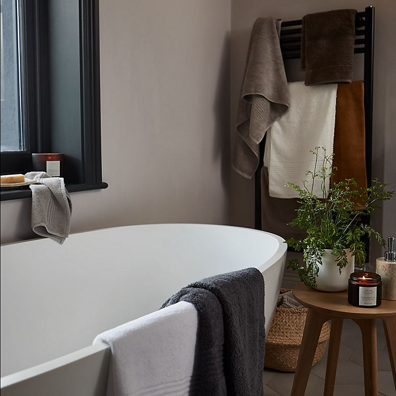 Selection of white, grey and brown towels and Apothecary candles in a modern bathroom
