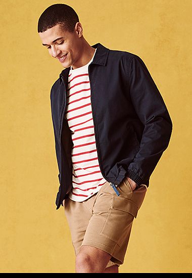 Man wearing red and white striped T-shirt, black Harrington jacket and camel-coloured cargo shorts