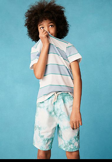 Boy wearing blue and white striped T-shirt and blue and white tie-dye swim shorts