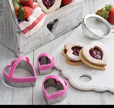 Lifestyle image showing heart-shaped cookie cutters and biscuits. Shop now