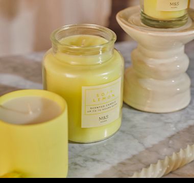 Group of yellow lemon-scented candles and candleholder. Shop now. 