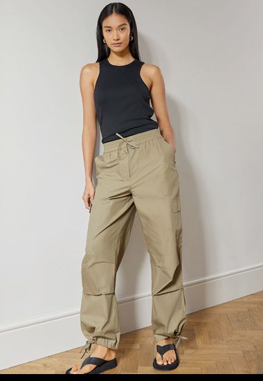 Woman wearing vest top with Y2K style cargo trousers. Shop now. 