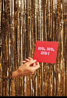 Hand poking out from a gold glitter curtain holding a gift card. Shop gift cards 