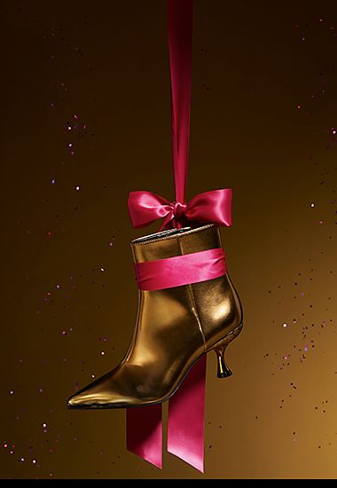 Gold ankle boot hanging from a ribbon. Shop women’s partywear