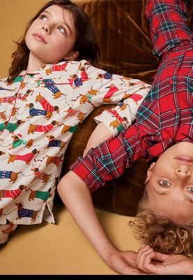 Girl and boy wearing Christmas pyjamas. Shop kids’ Christmas pyjamas.