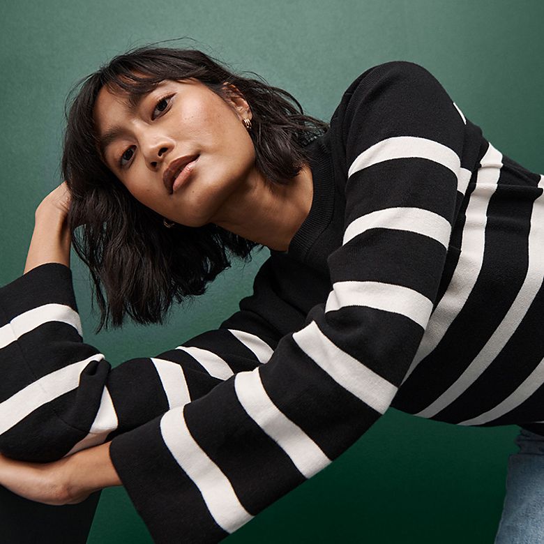 Woman wearing a striped jumper. Shop women’s knitwear 