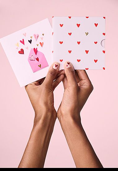 Woman’s hands holding two Valentine’s Day M&S gift cards. Shop now