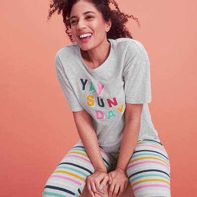 Woman wearing striped pyjama bottoms and graphic sleep tee